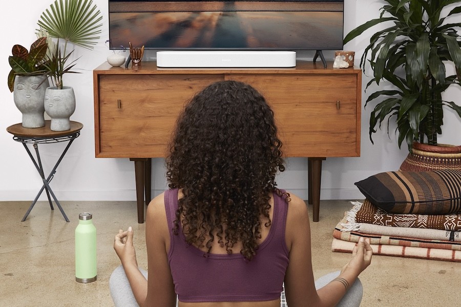 A woman meditating in her living room with the help of her whole-home audio system.