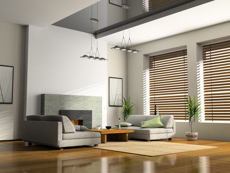  Image is of a modern living room with a grey furniture color scheme and custom-fitted blinds on each window.