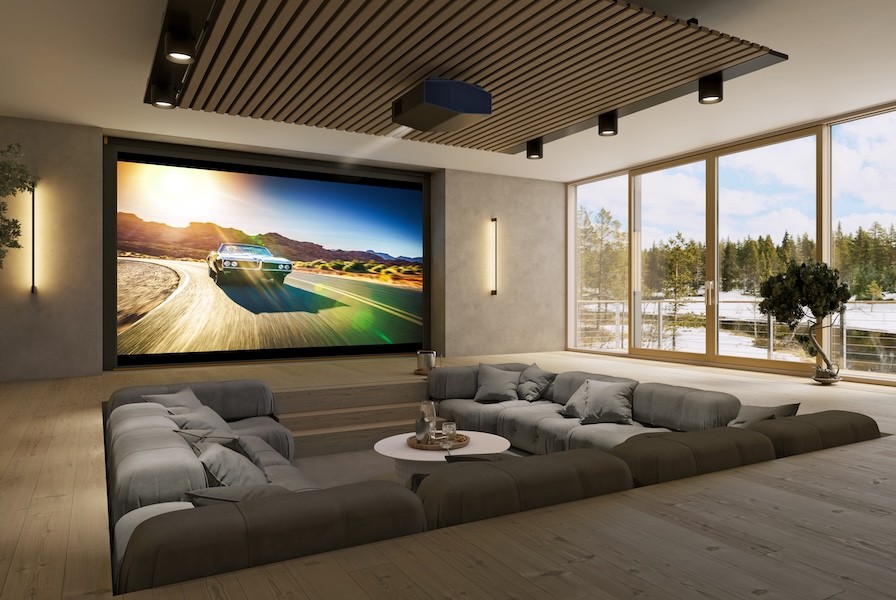 A home theater with conversation pit-style seating and a Sony projector playing a movie featuring a car driving.