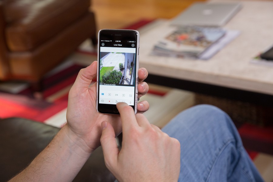 Hands holding a smartphone displaying the Luma App and live security camera feeds.